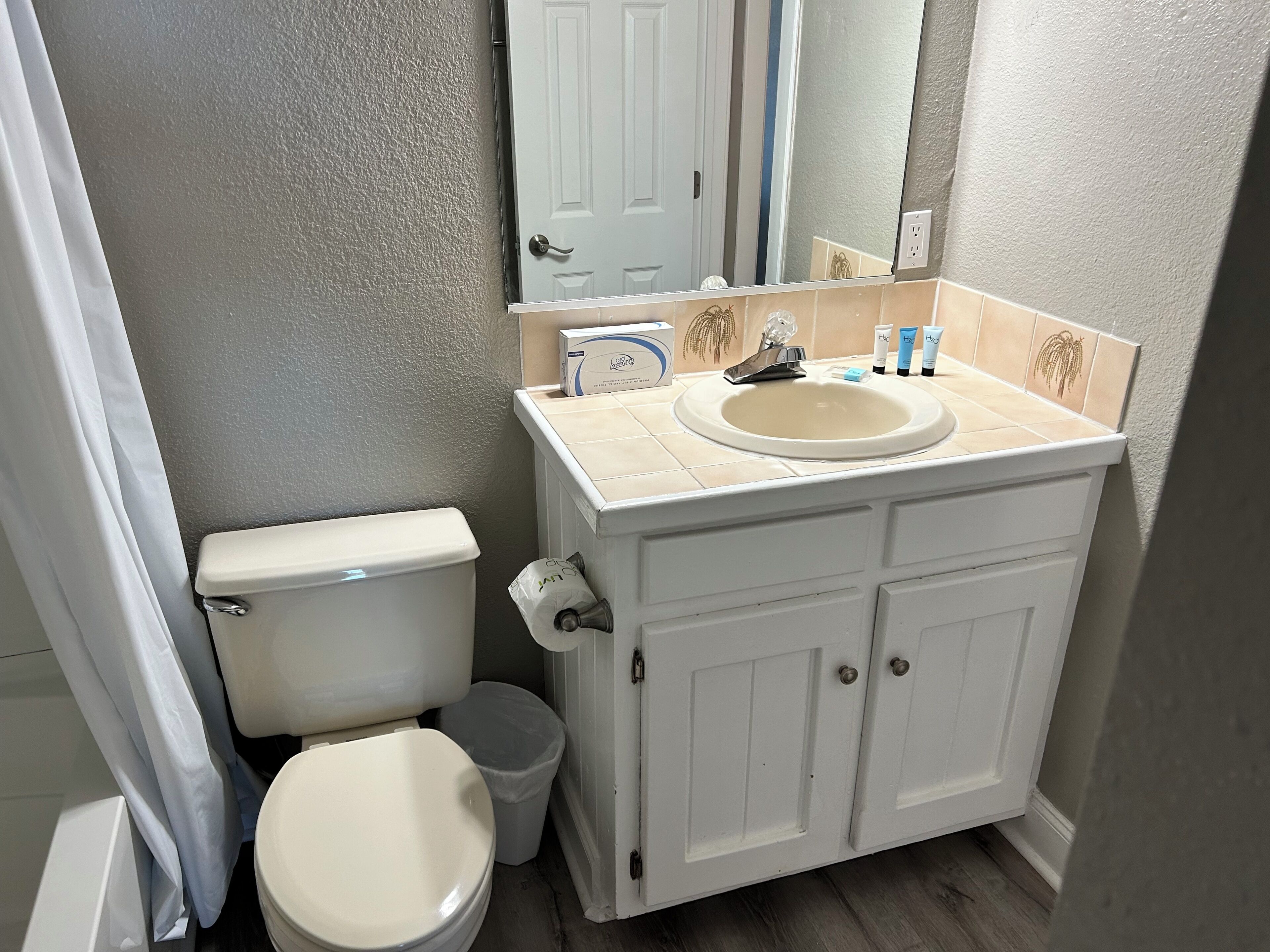 A bathroom with a toilet, sink, and cabinet.