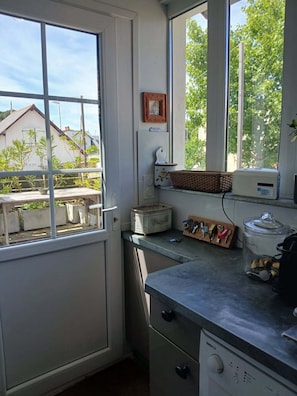 A kitchen with a window, a refrigerator, a sink, and a countertop with various items. - Chat Fleurs" family home Pornichet center very quiet (Pornichet)