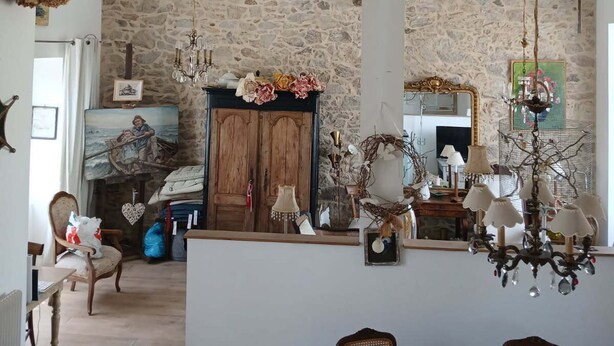 Une pièce spacieuse avec un plafond haut, un mur en pierre, des meubles en bois et un lustre.