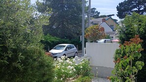 Un chemin de pierres mène à une maison où une voiture est garée dans l’allée.