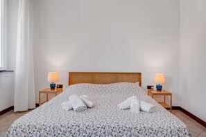 Ett hotellrum med en säng, två sängbord med lampor och ett fönster med gardiner.