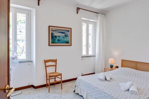 Une chambre à coucher avec un lit, une chaise, un tableau et une fenêtre.