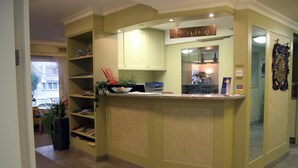A reception area with a reception desk, a sign above it, and a bookshelf with books and decorative items.