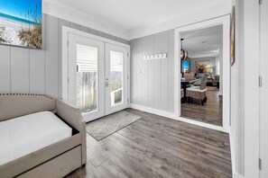 Une pièce avec un canapé, un plancher en bois, une porte donnant sur une vue agréable et un coin repas avec une lampe.