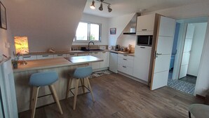Una cocina moderna con una isla central, taburetes de bar, microondas y tostadora.