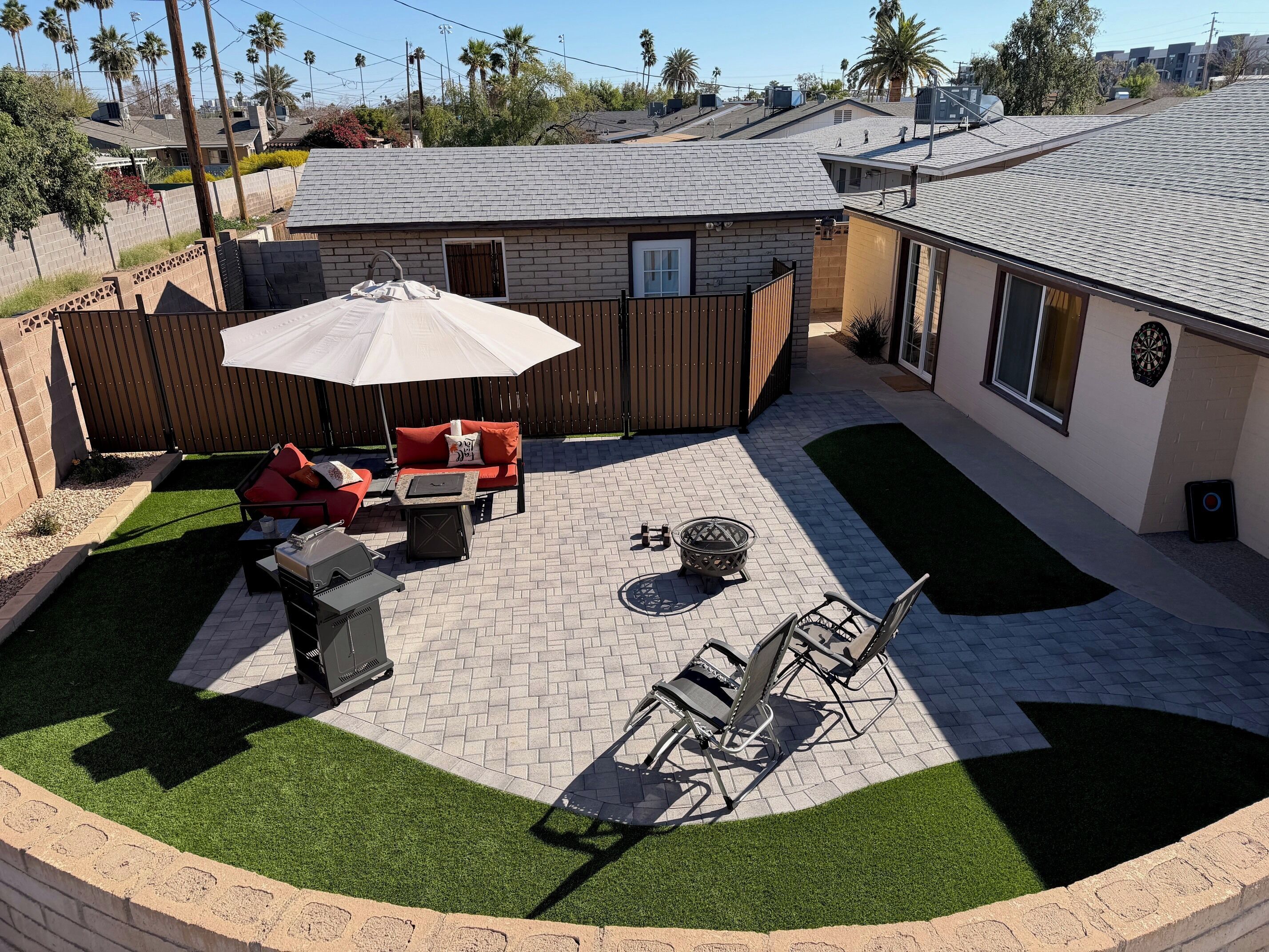 Un patio trasero con una parrilla, mobiliario exterior y una zona de estar cubierta.
