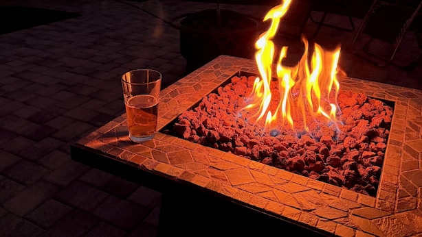En bålplads med flammer, et glas vand og en patio.