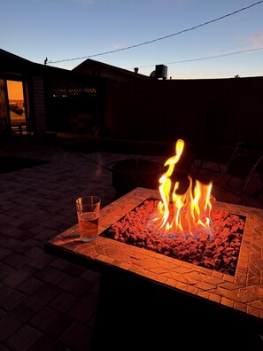 A fire pit with flames, a glass of water, and a patio area. - Charming 3-bedroom ASU -Spring Training-home in Tempe with AC (Tempe)
