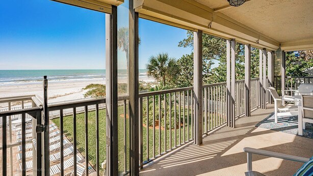 A covered balcony with a view of the beach, metal railings, and a seating area with chairs. - Sand Castle III 205- GULFFRONT CORNER UNIT! (Indian Shores)