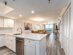 Een moderne keuken met een centraal eiland, een eetgedeelte met uitzicht en een woonruimte met een balkon.