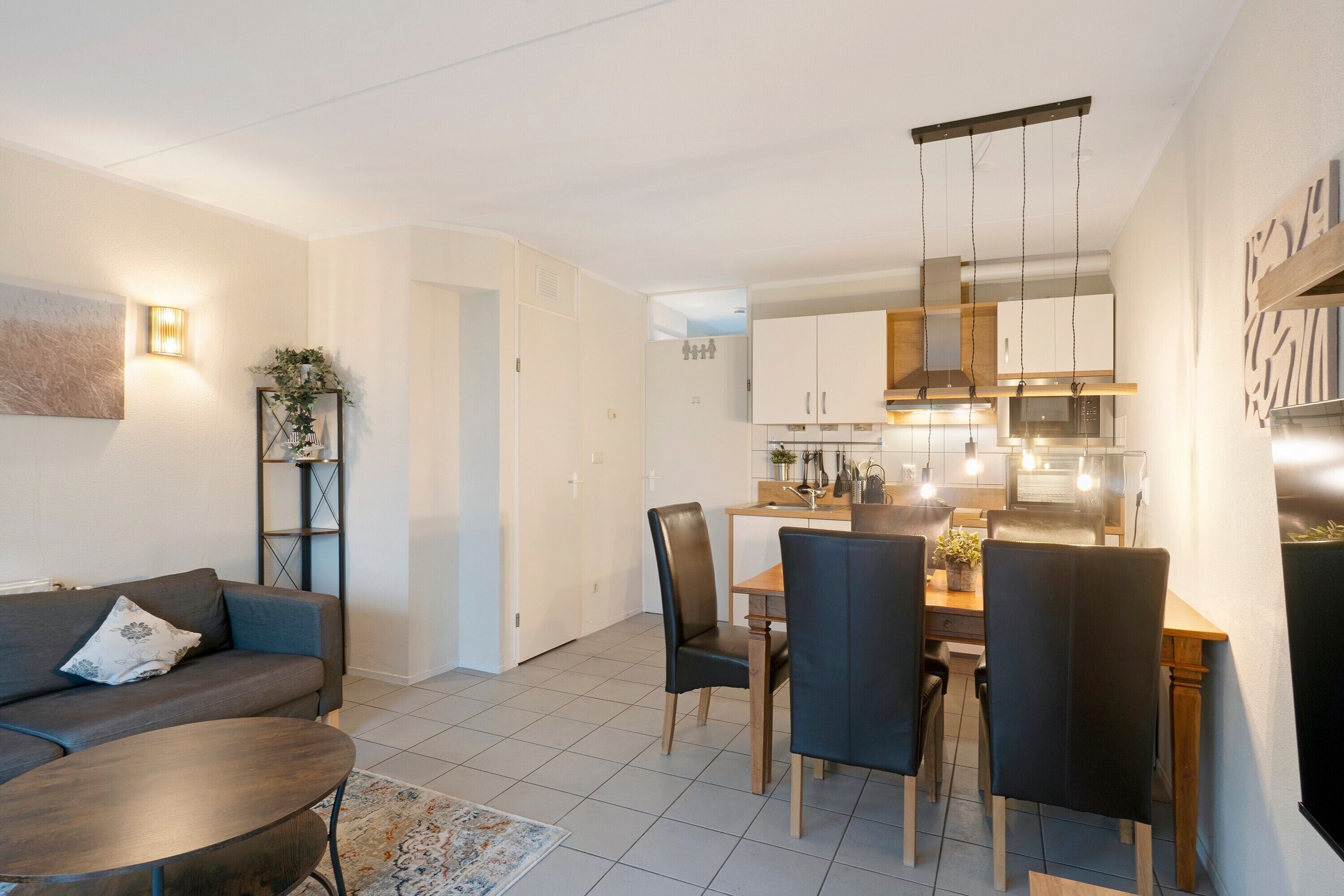Un salon moderne comprenant un canapé, une table basse et un coin repas avec des chaises et une table.