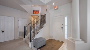A clean, modern interior with a staircase, white doors, and a beige carpet. - CP948 -6BR  Modern Home | Private Pool | Spacious (Davenport)
