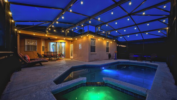 An indoor swimming pool with a glass ceiling, lounge chairs, and a small building with a door. - CP948 -6BR  Modern Home | Private Pool | Spacious (Davenport)