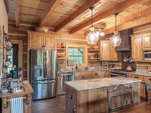 A spacious kitchen with wooden cabinets, stainless steel appliances, and a granite countertop.