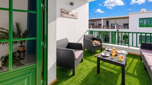 Ein Balkon mit Korbmöbeln, einem Tisch mit Frühstücksgebäck und Blick auf die Außenansicht des Gebäudes.