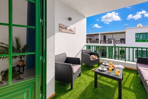 A balcony with wicker furniture, a table with breakfast items, and a view of the building's exterior. - Casa Lanzarote Luxury Stay • Beach 2 min • LVH (Playa Blanca)