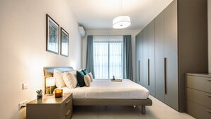 A modern bedroom with a bed, bedside table, lamp, and a window with curtains. - Bright and Modern 2BR Penthouse, St Julian's (Saint Julian's)