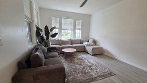 Una sala de estar con un sofá modular, una mesa de centro redonda y un ventilador de techo.