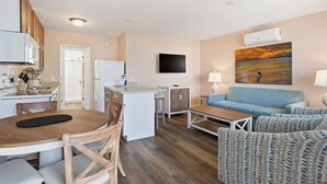 Un espacio habitable compacto con kitchenette, zona de comedor, sofá y televisor.