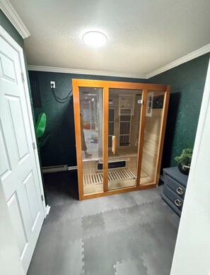 A room with a sliding glass door leading to a balcony, a small wooden bench, and a potted plant on a dresser. - The Joyful Escape | Playful 70s-Modern Retreat (Crewe)