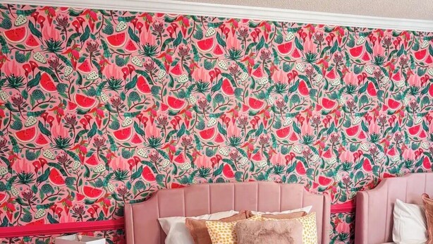 Ein Schlafzimmer mit einem Bett, Kissen, einem Nachttisch und einer Wand mit Muster.
