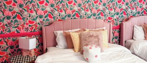 A bedroom with a bed, pillows, a bedside table, and a patterned wall.