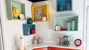 Eine Küche mit einem roten Schrank, einer Kaffeemaschine und diversen Küchenutensilien auf Regalen.