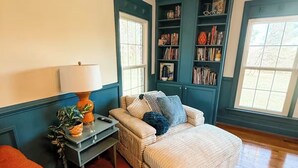 Ein gemütliches Wohnzimmer mit einer Couch, einem Teppich mit Muster und einem Bücherregal.