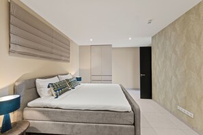 A modern bedroom with a large bed, bedside lamps, a wardrobe, and a door. - Cape Marie Luxury Apartments 231 B at Coral Estate (Willemstad)