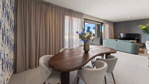 Ein modernes Wohnzimmer mit Esstisch, Stühlen, einer Couch und einem Fernseher.