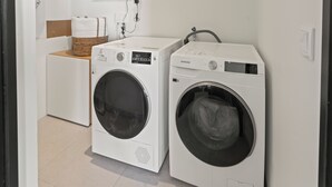 Zwei Waschmaschinen mit Frontlader in einem Waschraum, inklusive Wäschekorb und weißer Wand.