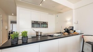Una cocina moderna con armarios blancos, electrodomésticos de acero inoxidable y encimera negra.