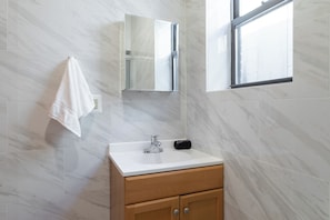 A bathroom with a white sink, wooden cabinet, and a towel hanging on the wall.