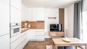 Una cocina moderna con armarios blancos, encimera de madera y horno empotrado.