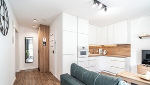 Una cocina moderna con armarios blancos, un detalle en madera y un horno empotrado.