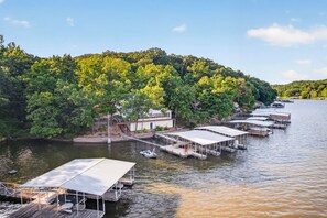 A lakeside property with multiple docked boats, a covered dock area, and a forested hillside. - Mimosa House - 5 bdrm house with large dock! (Rocky Mount)