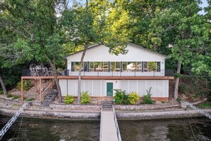 A houseboat with a covered deck, a green door, and a dock extending into a body of water. - Mimosa House - 5 bdrm house with large dock! (Rocky Mount)