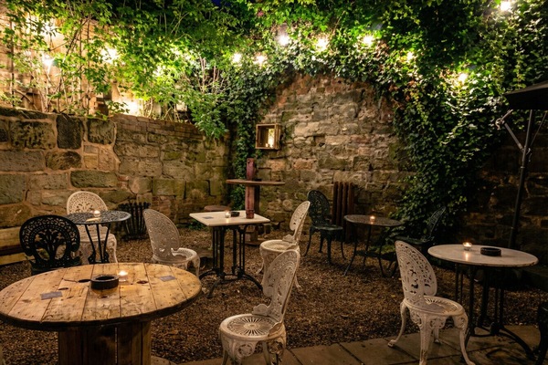 An enchanting candlelit courtyard wrapped in ivy and fairy lights nearby.