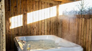 Un bain à remous dans une pièce en bois, avec vue sur les arbres à l’extérieur.