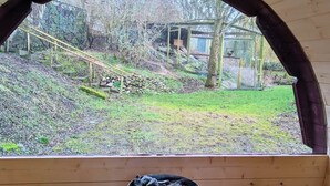 Une cabane en bois avec vue sur un jardin et une petite construction en arrière-plan.
