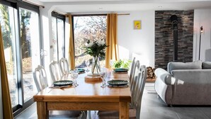 Un coin repas avec une table en bois dressée pour quatre personnes, un canapé et une cheminée.