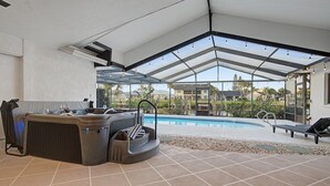 A modern outdoor area with a hot tub, a pool, and a covered patio. - Canal Front Retreat | Pool, Hot Tub, Dock + Game Room (Apollo Beach)