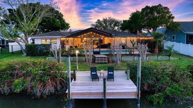 A house with a deck, a pool, and string lights. - Canal Front Retreat | Pool, Hot Tub, Dock + Game Room (Apollo Beach)
