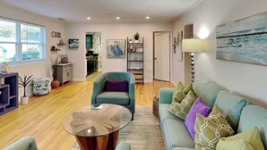A spacious living area with a sofa, armchairs, a coffee table, and a dining area in the background. - Spring Tide | Pet-Friendly, Large Deck, Great Location (Tybee Island)