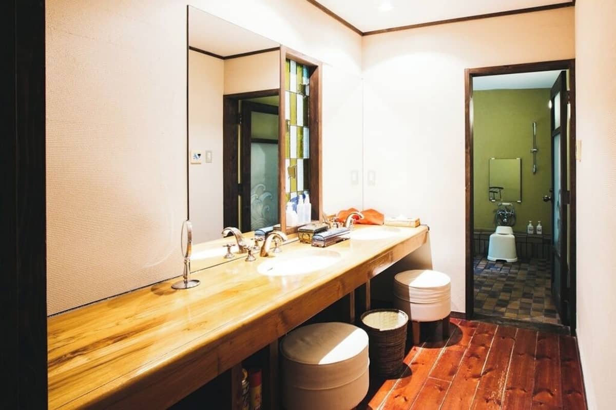 Ein Badezimmer mit einem Holzbidet, zwei Waschbecken, einem großen Spiegel und einem Schachbrettboden.