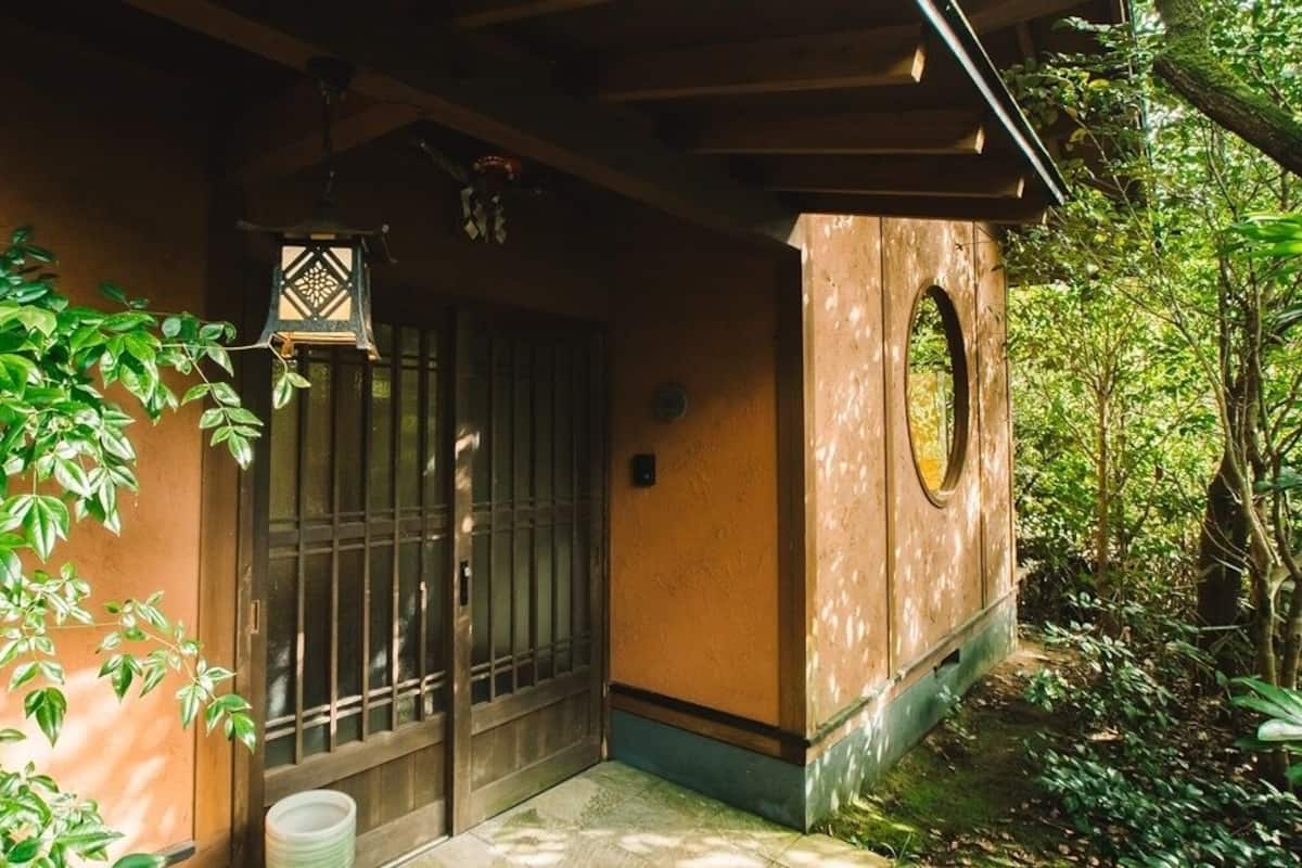 Eine Holzhütte mit einer vergitterten Tür, einem kleinen Rundfenster und einer hängenden Laterne.