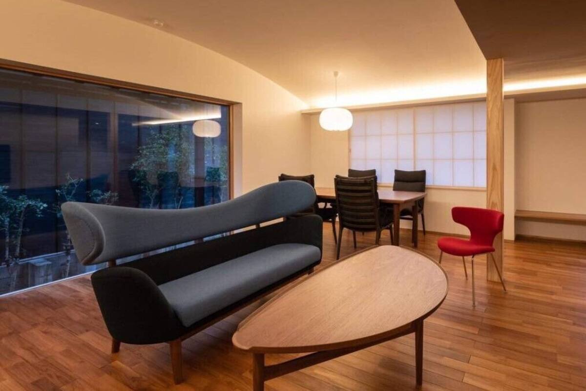Un salon moderne avec un canapé, une table à manger, des chaises et une grande fenêtre.
