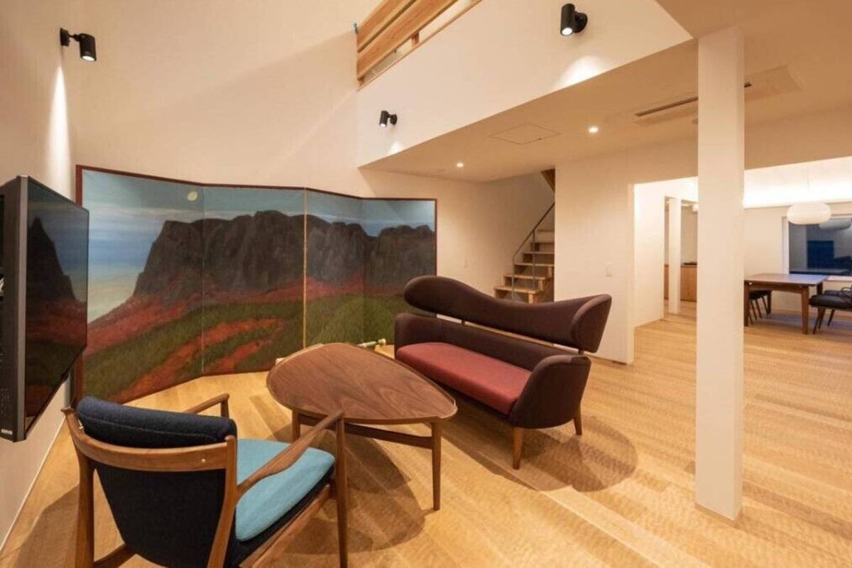 Un intérieur moderne avec un plancher en bois, un canapé, une table à manger et un escalier.