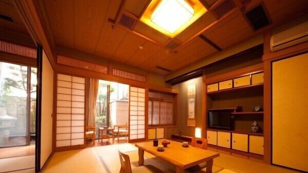 A traditional Japanese room with tatami flooring, a low wooden table, sliding doors, and a built-in shelf with storage boxes. - Beppu Onsen Shinhorii (Beppu)