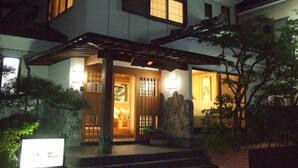 A two-story house with a covered entrance, a stone wall, and a signboard. - Beppu Onsen Shinhorii (Beppu)